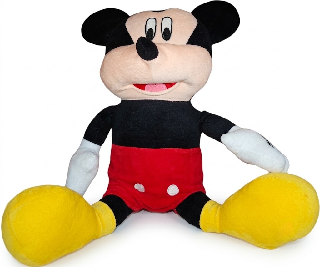 A seated plush toy of Mickey Mouse in his iconic red shorts with white buttons and yellow shoes.